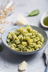 Plate of pasta fusilli with pesto sauce and parmesan cheese on gray concrete background