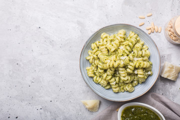 Plate of pasta fusilli with pesto sauce on gray concrete background