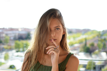 Pretty girl showing a sign of silence gesture putting finger in mouth at outdoors