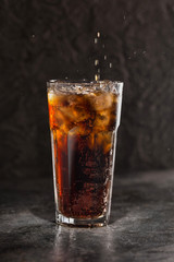 Glass of coke with ice on a dark background. Carbonated beverages. Selective fokus.