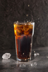 Glass of coke with ice on a dark background. Carbonated beverages. Selective fokus.