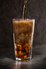 Glass of coke with ice on a dark background. Carbonated beverages. Selective fokus.