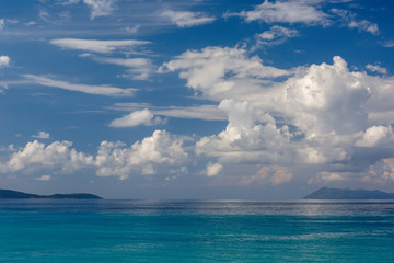 Fototapeta na wymiar Azure sea, white Cumulus clouds and mountains on the horizon