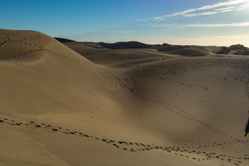Undefined woman and child walking in yellow sandy dunes of Maspalomas, Gran Canaria, Spain