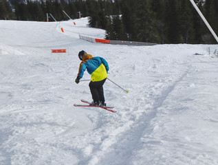Child skier performs a high jump with the ski in Chopok, Slovakia. Winter season, colorful jacket. Small boy jumping on downhill skis. Big jump