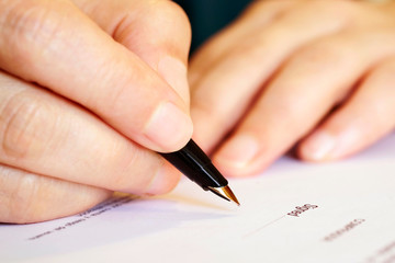 signing at  document with gold pen closeup