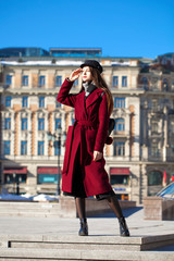 Beautiful girl in stylish in a long burgundy coat