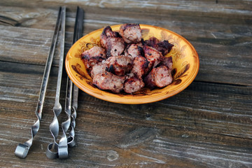 Shish kebab in a plate. On the brown wooden table