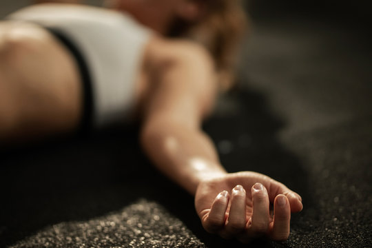 Close Up Of Exhausted Athlete Resting On The Floor After Sports Training.