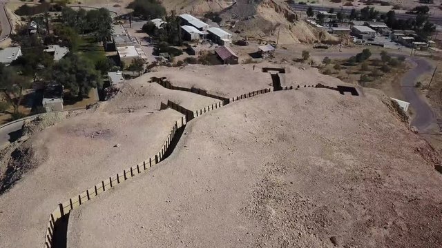 Aerial drone shot Tilt revel from Infantry canals and Military trenches hill to reveal Kibbutz Yotvata Edom mountains Edomites Arava at the Negev Israel at Sunset