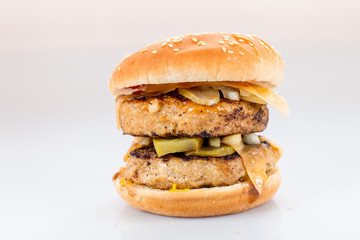 cheeseburger with beef cutlet, bacon, tomatoes and cheese slices, seasoned with sauce and green salad for a restaurant menu on a white isolated background