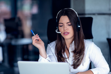 Portrait of happy smiling female customer support phone operator at workplace.