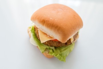 cheeseburger with beef cutlet, bacon, tomatoes and cheese slices, seasoned with sauce and green salad for a restaurant menu on a white isolated background