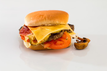 cheeseburger with beef cutlet, bacon, tomatoes and cheese slices, seasoned with sauce and green salad for a restaurant menu on a white isolated background