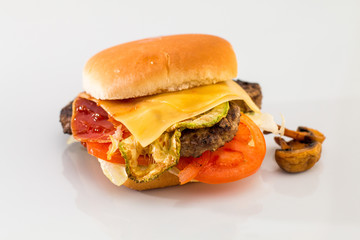 cheeseburger with beef cutlet, bacon, tomatoes and cheese slices, seasoned with sauce and green salad for a restaurant menu on a white isolated background