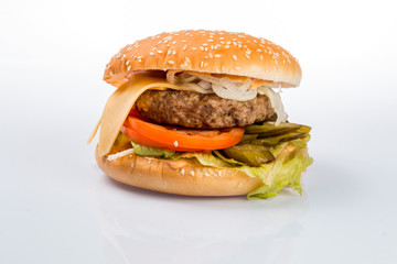 cheeseburger with beef cutlet, bacon, tomatoes and cheese slices, seasoned with sauce and green salad for a restaurant menu on a white isolated background