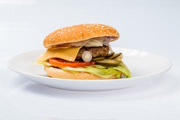 cheeseburger with beef cutlet, bacon, tomatoes and cheese slices, seasoned with sauce and green salad for a restaurant menu on a white isolated background