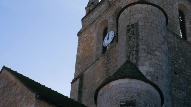 Gimbal shot of a antique church with a big clock showing 12AM
