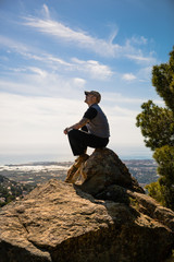 Obraz premium Hiker sitting on a rock with great view, side view
