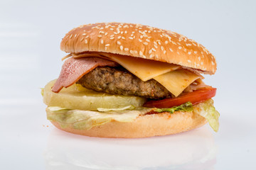 cheeseburger with beef cutlet, bacon, tomatoes and cheese slices, seasoned with sauce and green salad for a restaurant menu on a white isolated background