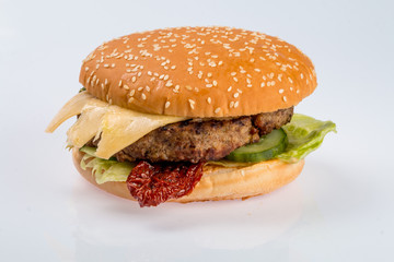 cheeseburger with beef cutlet, bacon, tomatoes and cheese slices, seasoned with sauce and green salad for a restaurant menu on a white isolated background