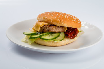 cheeseburger with beef cutlet, bacon, tomatoes and cheese slices, seasoned with sauce and green salad for a restaurant menu on a white isolated background