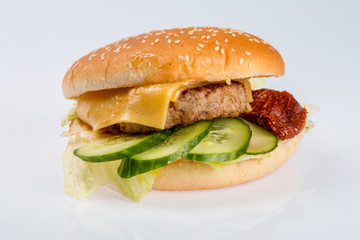 cheeseburger with beef cutlet, bacon, tomatoes and cheese slices, seasoned with sauce and green salad for a restaurant menu on a white isolated background