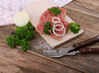 slice of bread with minced meat, parsley and onions - on rustic wooden table - breakfast bread -...