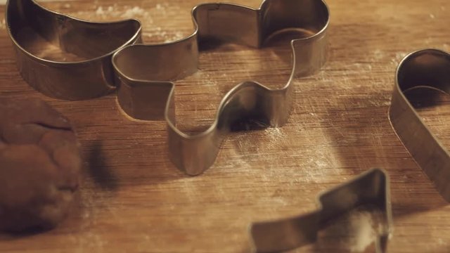 Macro shot of cookie cutters in festive Christmas shapes & gingerbread dough in a kitchen