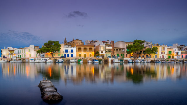 Porto Colom, Mallorca fishing boats and buildings reflected in a still Mediterranean sea