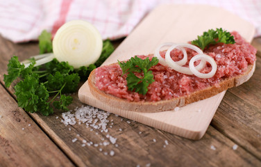 slice of bread with minced meat, parsley and onions - on rustic wooden table - breakfast bread - pork mett