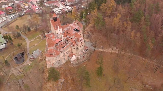 Colors of Autumn on the Romanian landscape as a drone circles high above Dracula's Castle. Tourists and horror movie enthusiasts visit the location frequently. Aerial view.