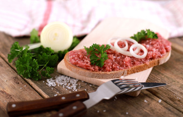 slice of bread with minced meat, parsley and onions - on rustic wooden table - breakfast bread - pork mett
