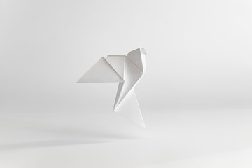 Origami dove made of white paper on white background. Minimal concept. - obrazy, fototapety, plakaty