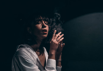 brunette smokes in a bar under the lamp