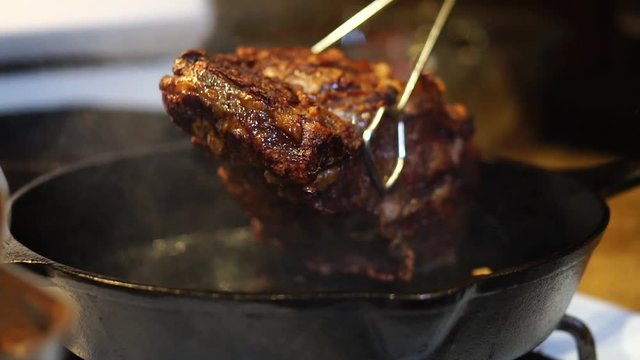 Juicy chunk of seared beef steak frying in cast iron skillet, Slowmo Close Up