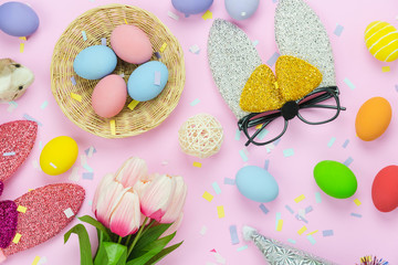Fototapeta na wymiar Table top view shot of decorations Happy Easter holiday background concept.Flat lay arrangement close up colorful eggs & confetti with costume decor for party festival on modern rustic pink paper.