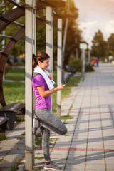 Active female jogger resting and using smartphone