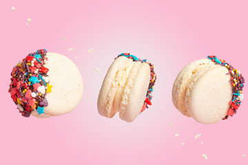 White French Macaroons, Sweet and colorful French macaroons are falling or flying in motion. On a pink background, with particles in motion