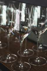 Crop shot of rows of a restaurant wine glasses in dark style as a concept