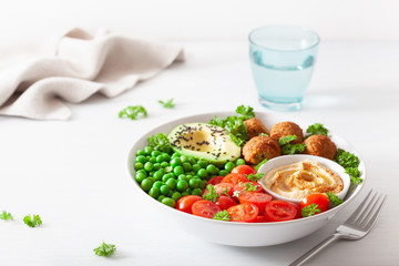healthy vegan lunch bowl with falafel hummus tomato avocado peas