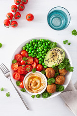 healthy vegan lunch bowl with falafel hummus tomato avocado peas