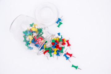 The colorful push pins and glass bottle put on white background,