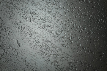 Image drops of a water on a silver metal surface.