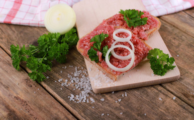 slice of bread with minced meat, parsley and onions - on rustic wooden table - breakfast bread -...