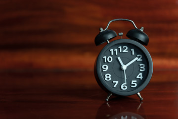 Black Alarm clock on wooden floor.