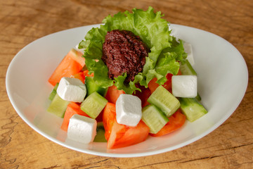 Greek salad with tomatoes, cucumbers, feta cheese and olive paste in lettuce leaf.