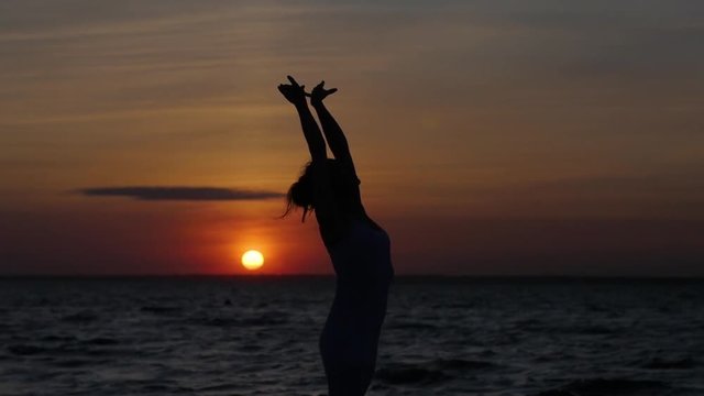 silhouette of a woman who dances against the backdrop of the sunset and the sea