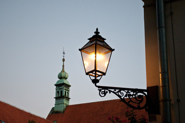 Fototapeta na wymiar Lit lantern and church spire, Old Town, Zagreb, Croatia