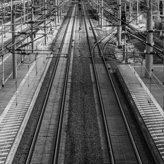 Fototapeta na wymiar Perspective view of railway tracks with overhead lines next to a platform